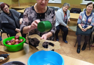 Seniorzy z Klubu "Senior+" podczas lania wosku w czasie imprezy andrzejkowej.